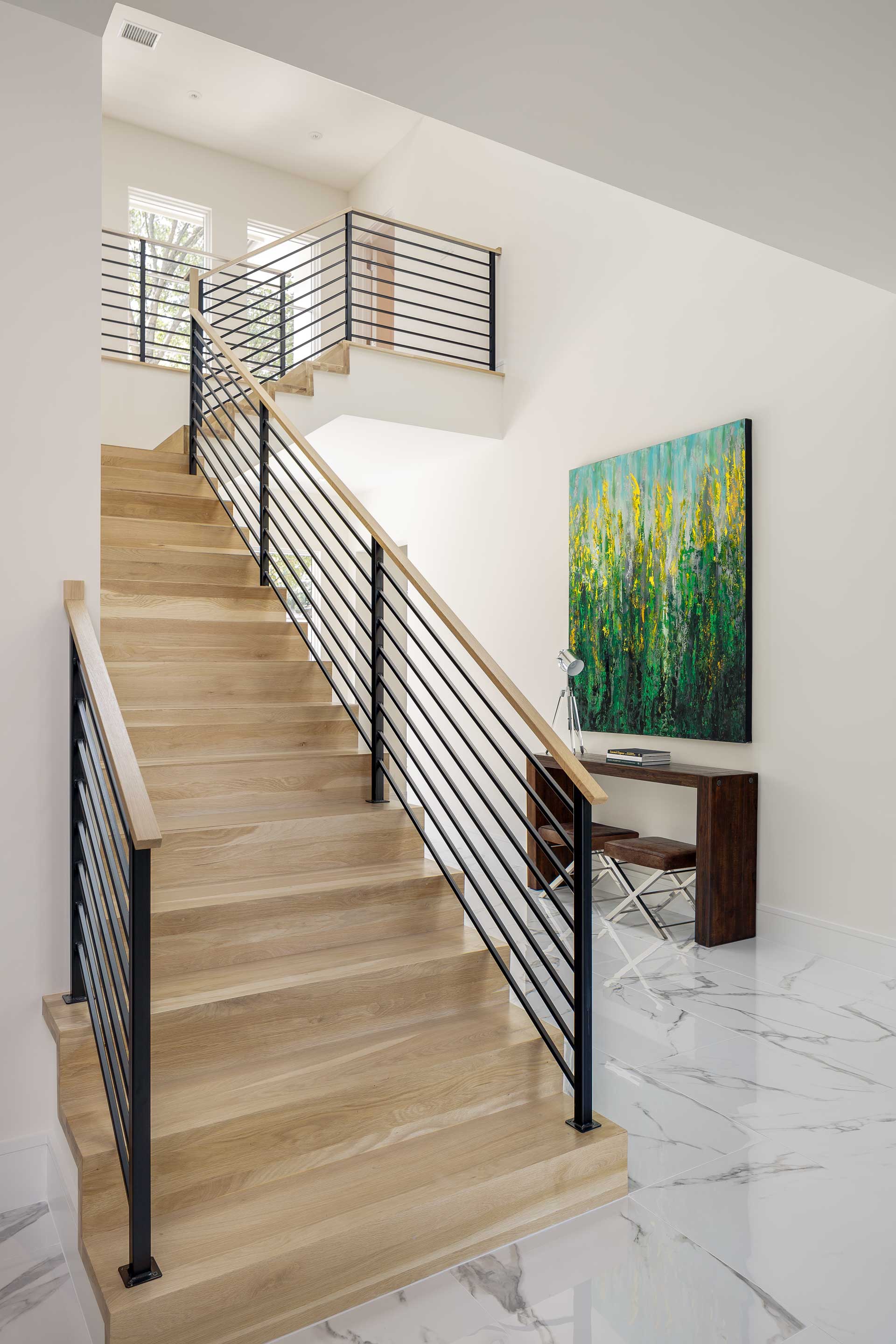 a staircase with a round table and a vase of flowers