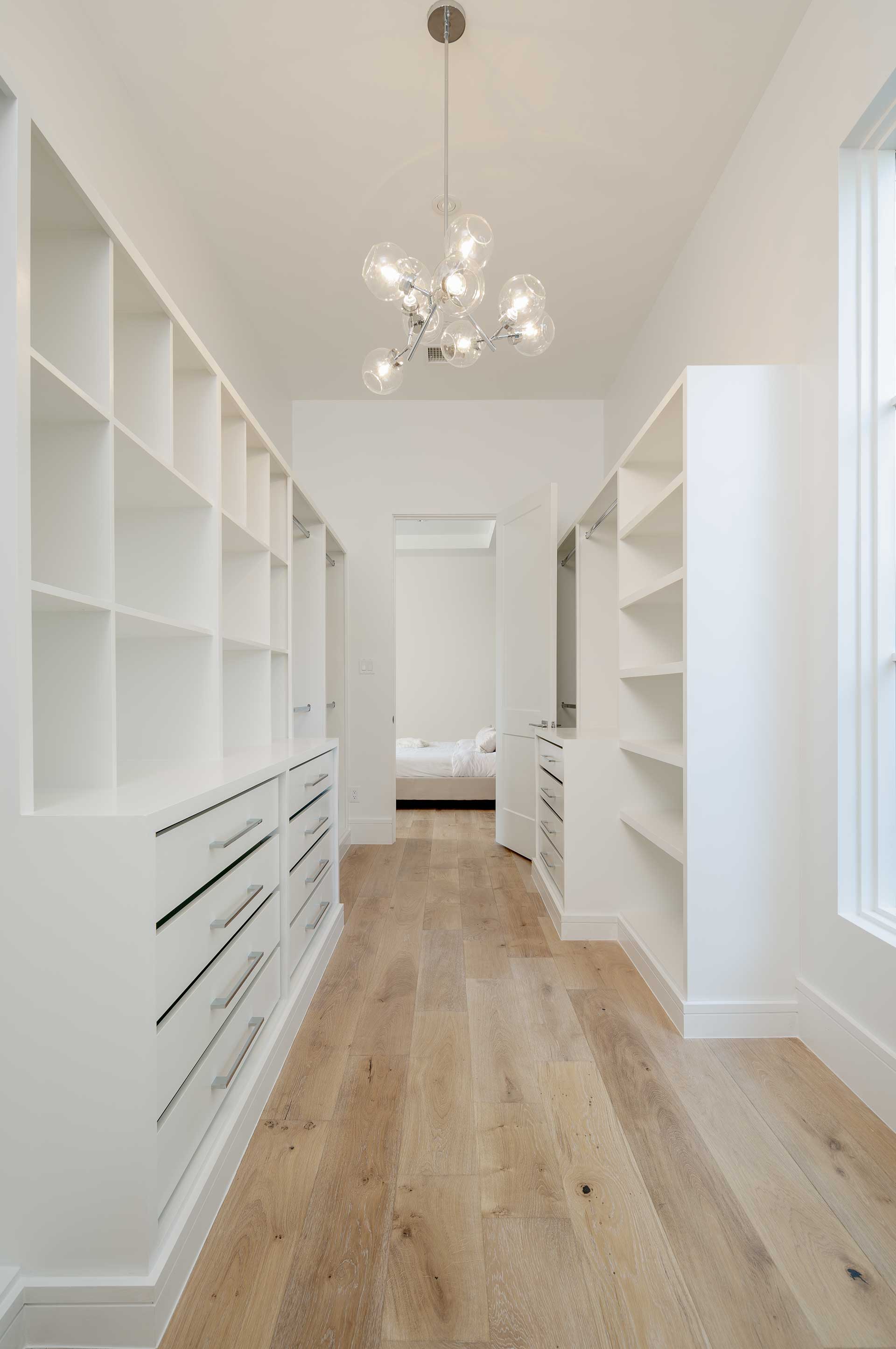 a white closet with shelves and a wood floor