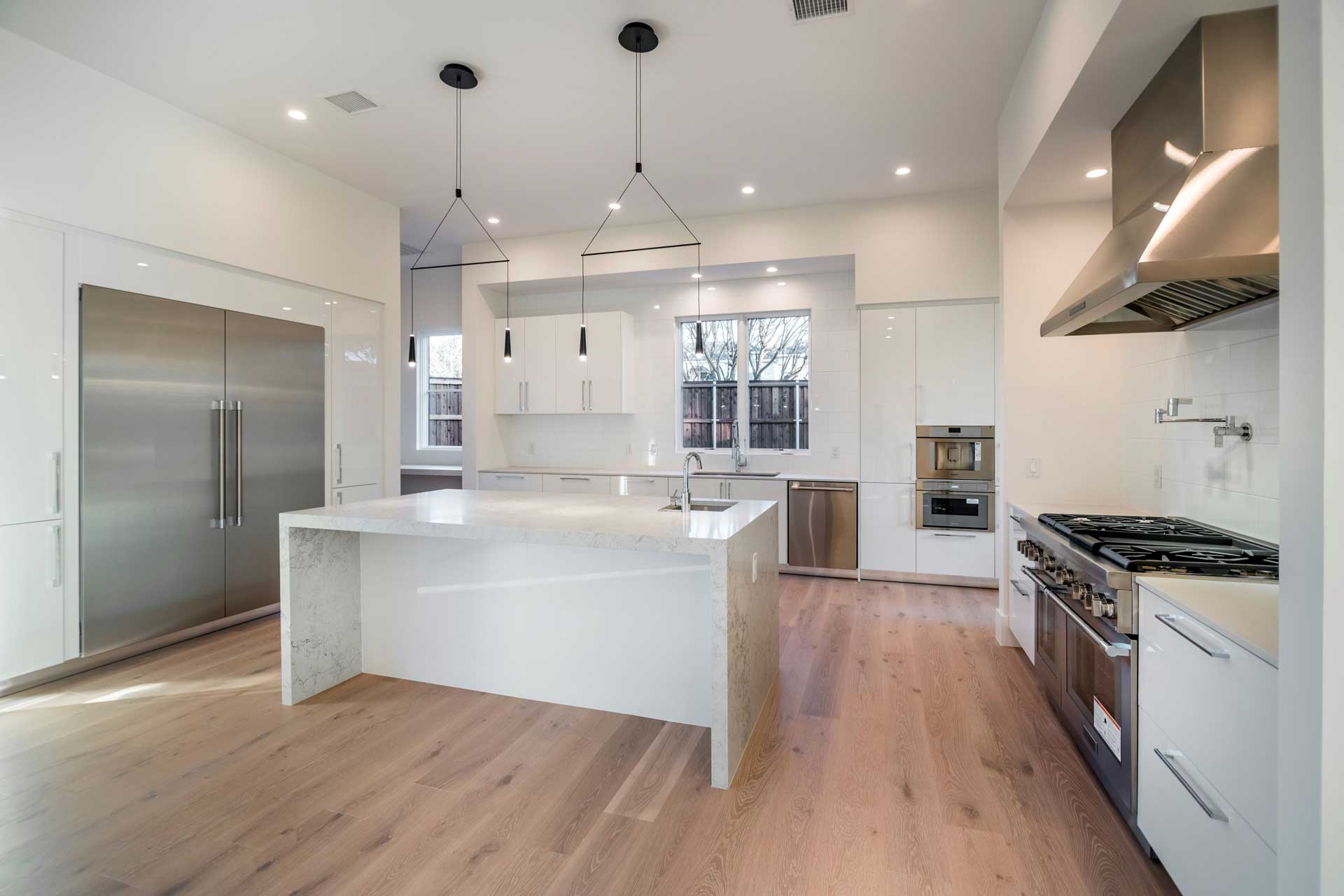 a large white room with a wood floor and a kitchen