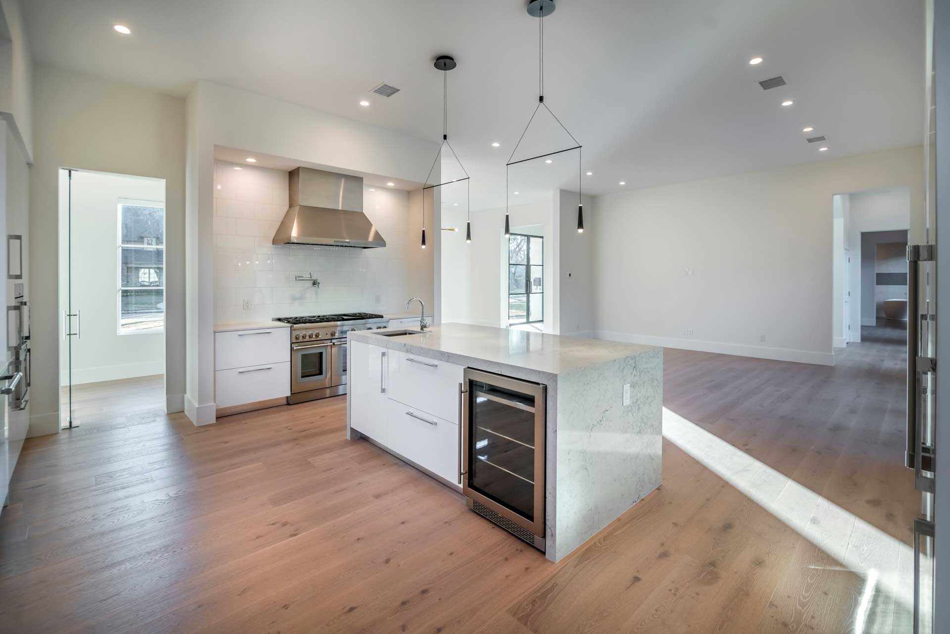 a large white room with a wood floor and a kitchen