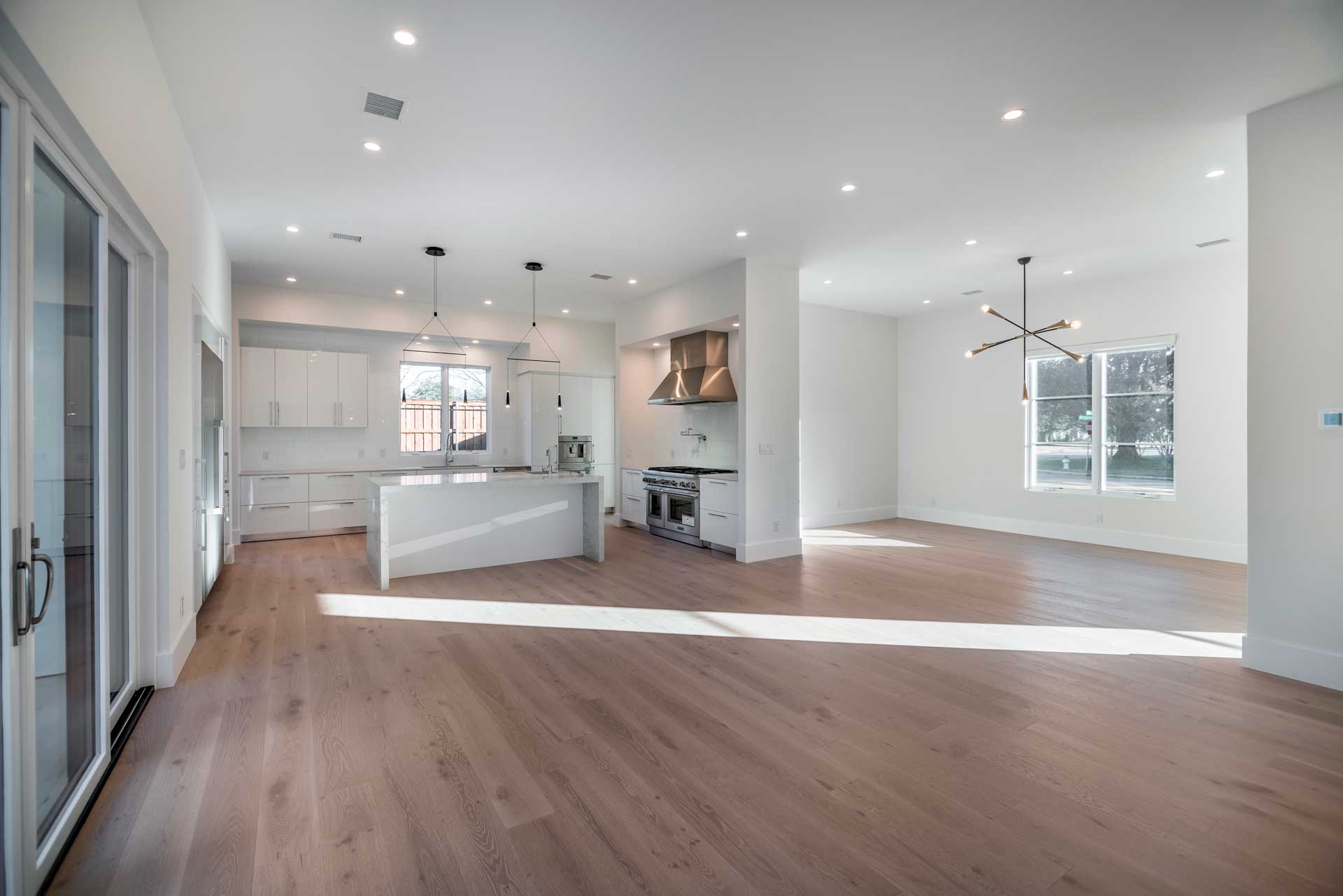 a large white room with a wood floor and a kitchen