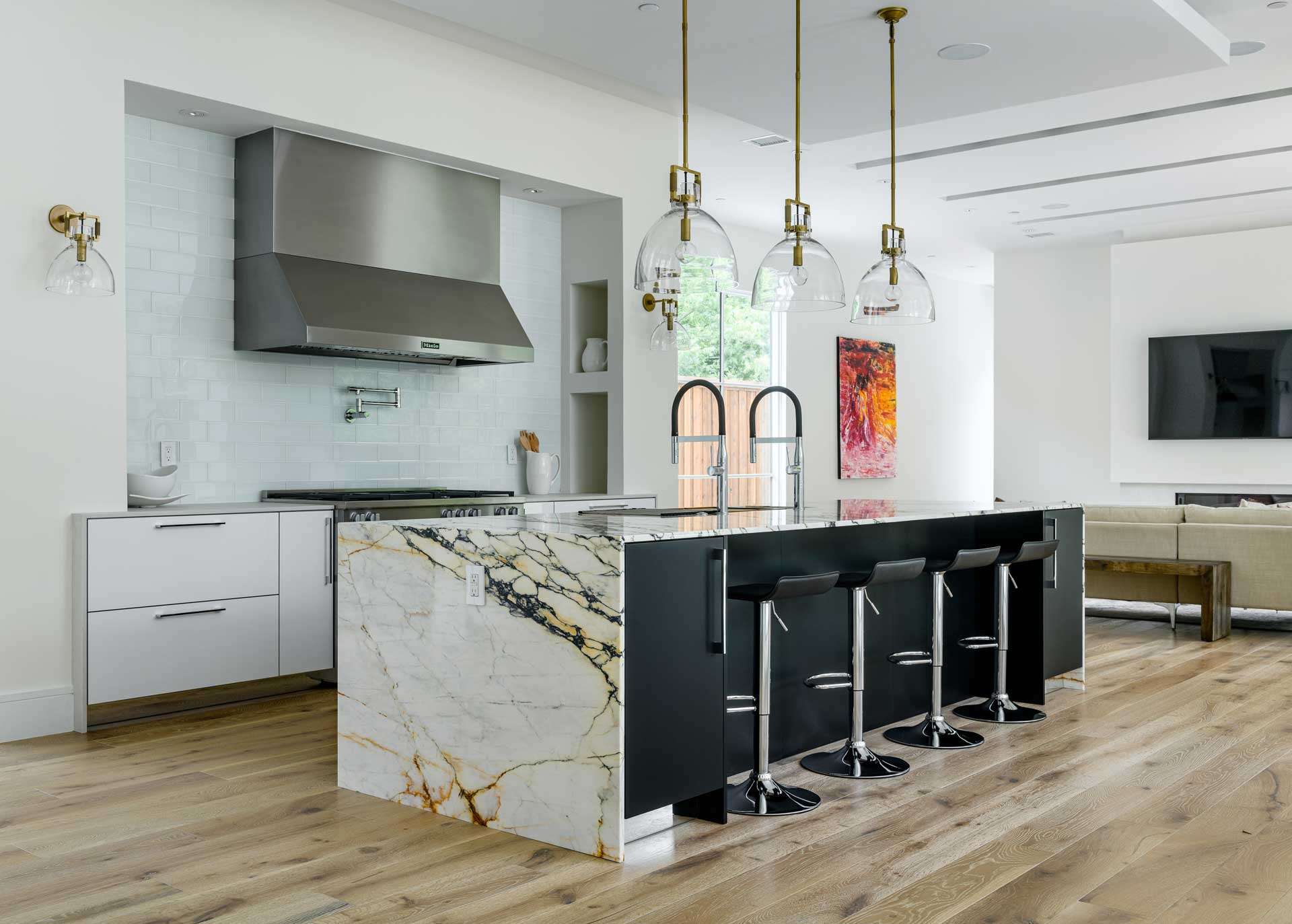 a kitchen with a marble island and black stools