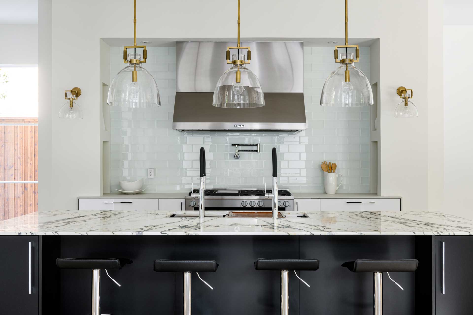 a kitchen with a marble island and black stools