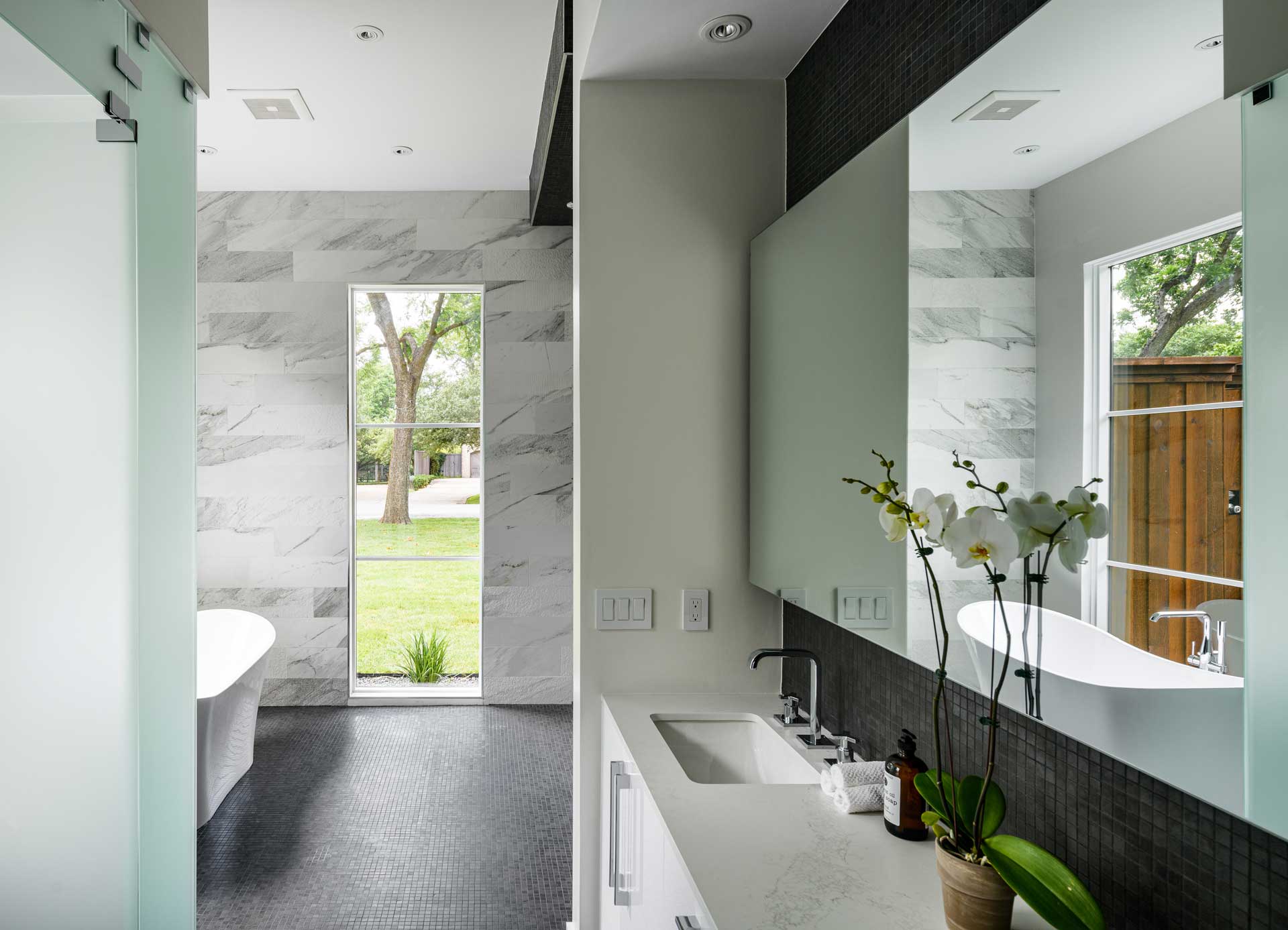 a bathroom with white cabinets and black tile