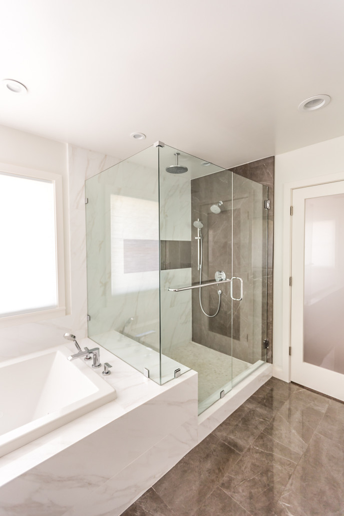 A spacious bathroom featuring a sleek glass shower door, enhancing the modern aesthetic of the room.