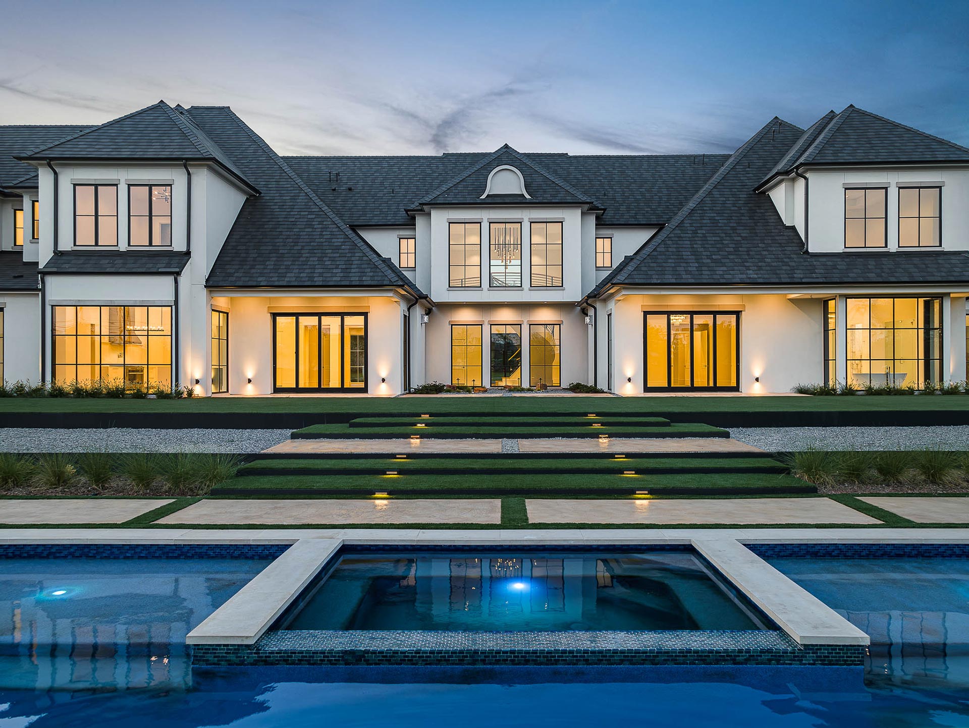 A spacious home featuring a pool and an expansive driveway, showcasing a luxurious outdoor living environment.