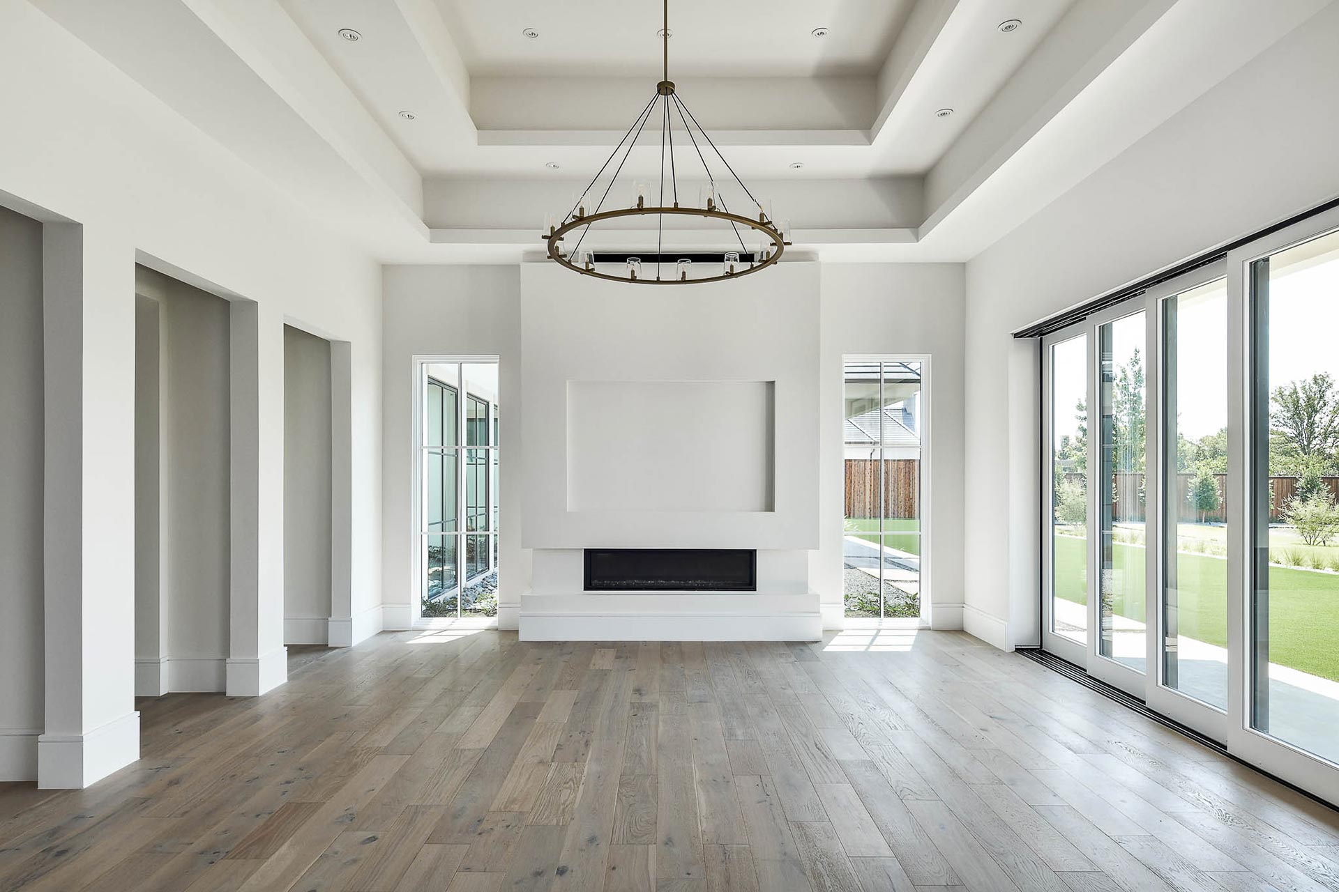 A spacious living room featuring hardwood floors, a cozy fireplace, and ample natural light streaming through large windows.